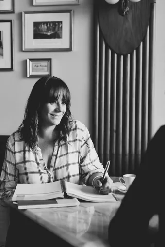Keely Capel taking notes during a one-to-one conversation across a café table